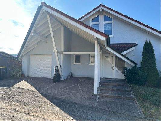 Hausansicht mit Zugang Garage und Stellplatz