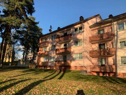 Außenansicht des dreistöckigen Hauses mit Balkonen und Bäumen vor dem Haus