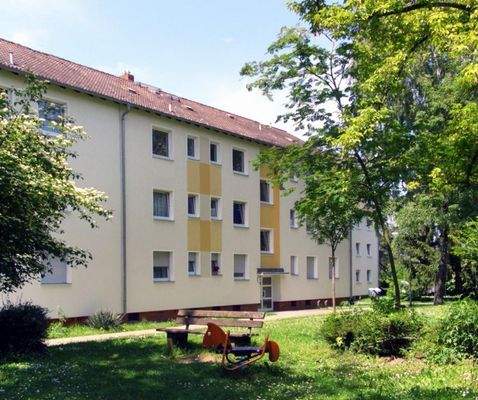 Hausansicht eines Mehrfamilienhauses, umgeben von grüner Wiese.