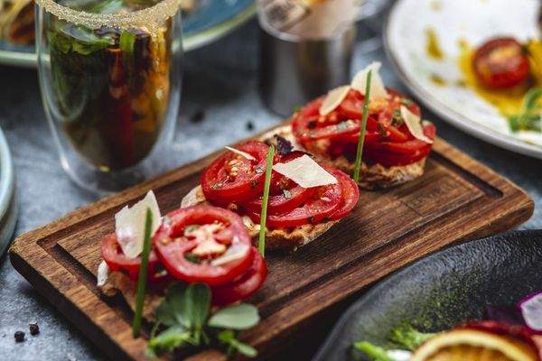 seitenansicht-bruschetta-mit-tomaten-basilikum-fruhlingszwiebeln-und-parmesan-auf-einem-brett