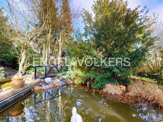 Idyllischer Teich mit kleiner Verbindungsbrücke zum Gartenhaus