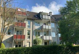 Außenansicht des Mehrfamilienhauses mit Balkonen und Grünflächen 