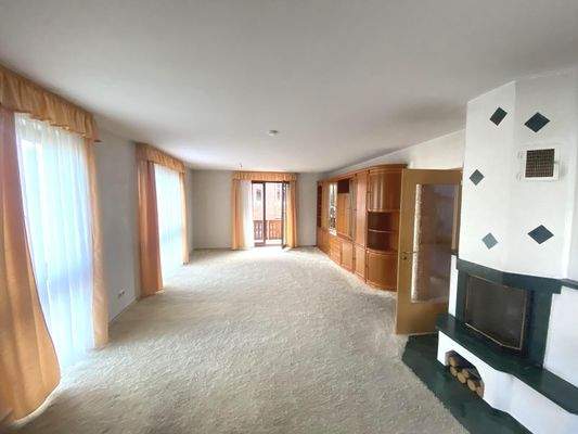 großes Wohnzimmer mit Balkonzugang und Kamin