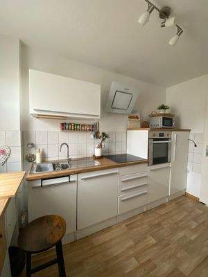 Mietereigene Küchenzeile mit weißen Fronten und einer Arbeitsplatte aus hellem Holz.jpg