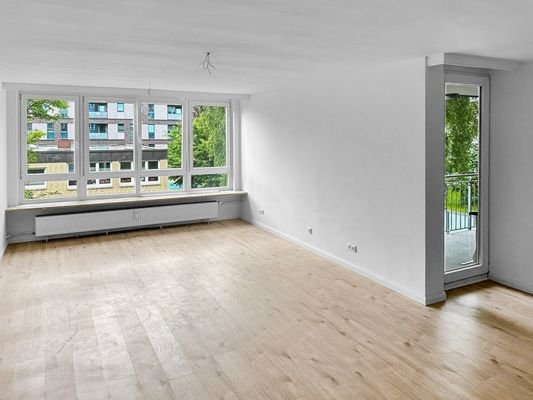 Wohnzimmer mit großer Fensterfront und Balkonzugang