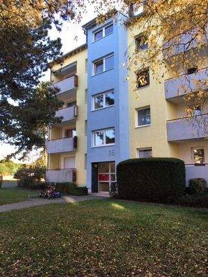 Gebäude Vorderseite des mehrstöckigen Wohnhauses umgeben von Grünanlagen mit Bäumen und Sträuchern