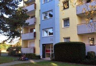 Gebäude Vorderseite des mehrstöckigen Wohnhauses umgeben von Grünanlagen mit Bäumen und Sträuchern