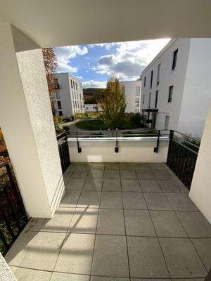 Balkon mit grauen Bodenfliesen mit Blick in die Grünanlage.JPG