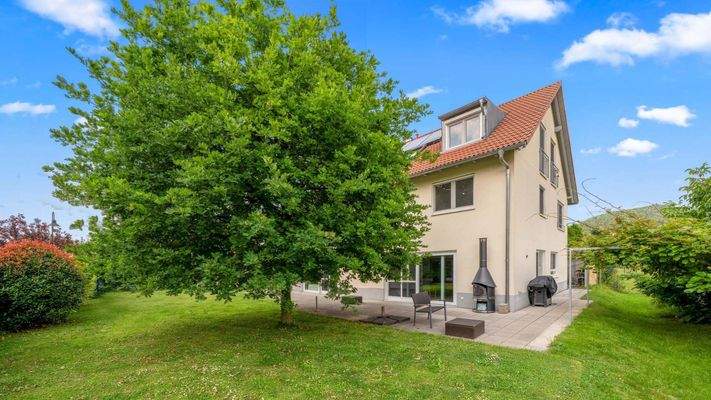 Außenbereich mit großer Grünfläche und breiter Terrasse