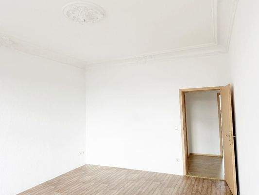 Wohnzimmer mit Stuckdecke und Blick Richtung Flurbereich