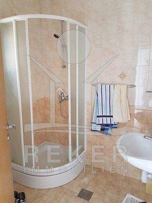 Das Badezimmer ist mit hellen Fliesen auf dem Boden und den Wänden versehen worden.