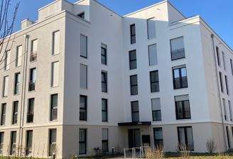 Vorderansicht eines weißen mehrstöckigen Gebäudes mit Fenstern und Hauseingang