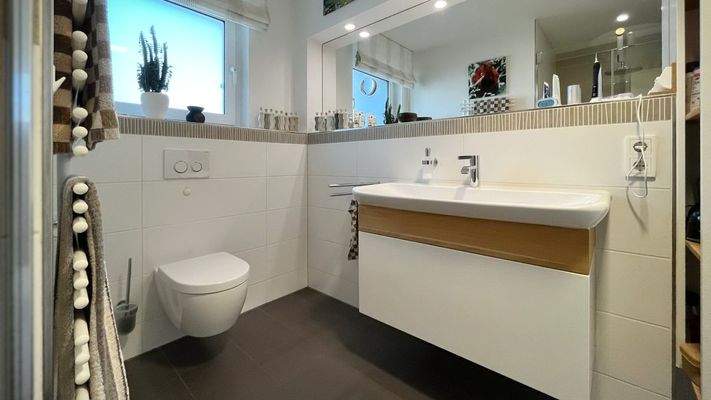 Tageslichtbad mit großformatigen Fliesen und modernen Armaturen