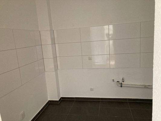 Küche mit grauen Bodenfliesen und weißen Wandfliesen