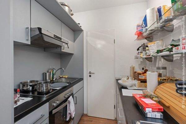 Halboffene Küche mit komplett ausgestatteter Einbauküche und angeschlossenem Abstellraum.