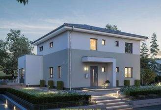 Stimmungsvolle Frontansicht eines massa haus Fertighauses bei Dämmerung, beleuchtet mit warmem Licht