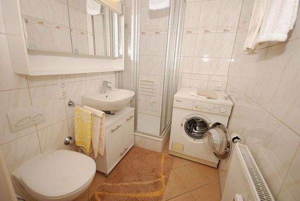Badezimmer mit Duschkabine und Waschmaschine