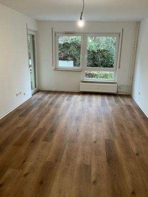 Wohnzimmer mit Bodenbelag in Holzoptik, Wände weiß angelegt