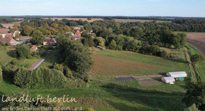 Grundstück mit Gewächshäusern und Dorf im Hintergr
