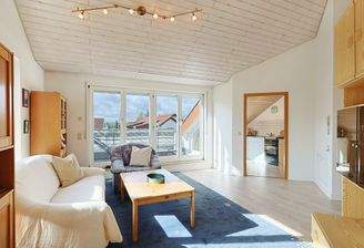 Lichtdurchfluteter Wohnbereich mit Blick zur Küche und dem Balkon