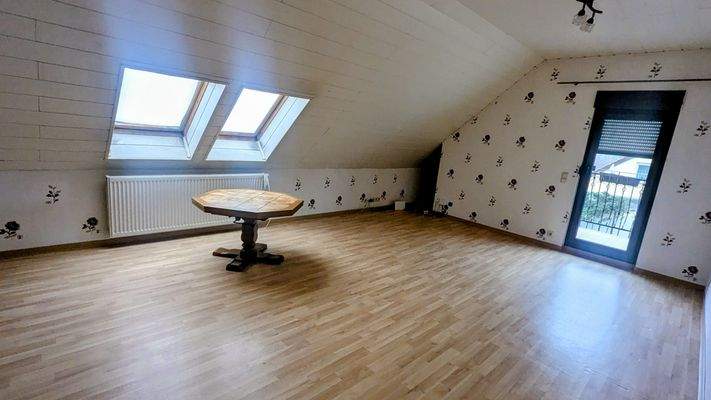 großer Wohnraum im Dachgeschoss mit Zugang zum Balkon
