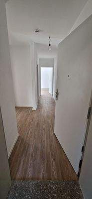 Blick in den Eingangsbereich, Flur_mit hellbraunen Vinylboden und weißen Wänden.jpg