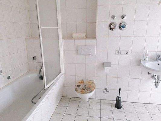 gefliestes Bad mit Wanne und Fenster