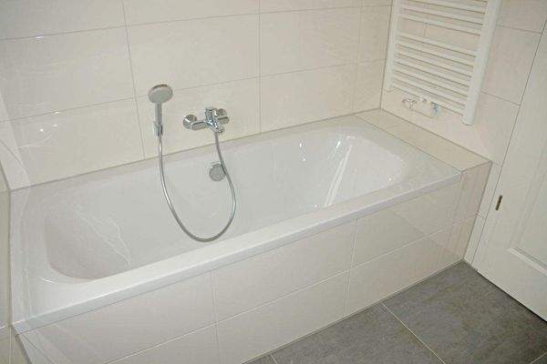 gefliestes Bad mit Wanne und Fenster