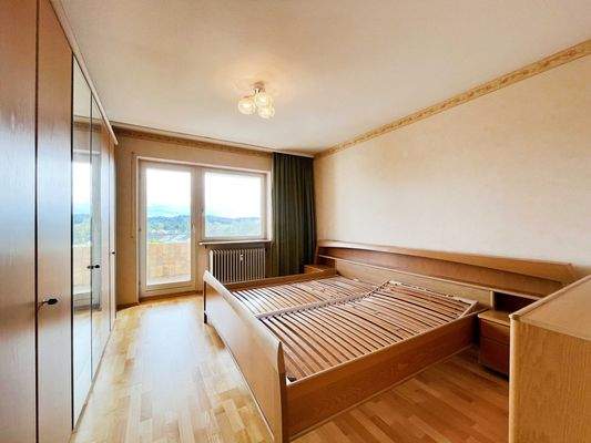 Schlafzimmer mit Echtholzparkett und Zugang zum Balkon