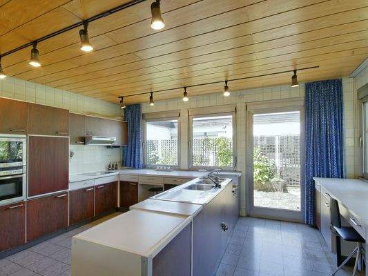 Praktisch aufgeteilte Wohnküche mit Fensterfront zur separaten Terrasse