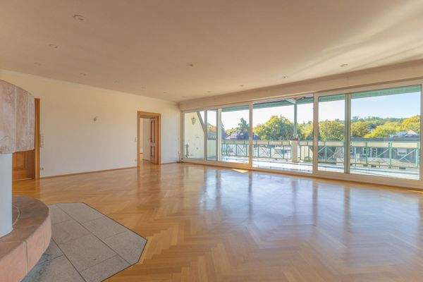 Großes Wohnzimmer mit Kamin und Zugang zum großen, 
überdachten Balkon