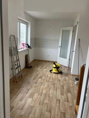 Küche mit weißen Wänden, weißem Fliesenspiegel, Fenster und PVC Boden in Holzoptik