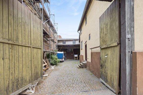 Toreinfahrt in den Hof, im Hintergrund große Scheune 