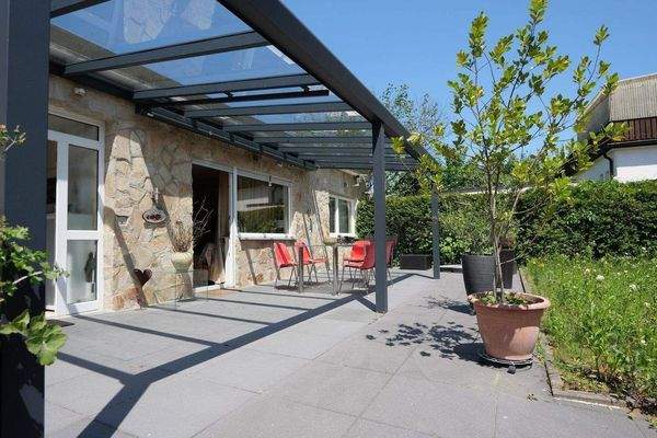 überdachter Sitzbereich auf der sonnigen Terrasse