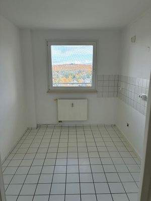 Beispielhaftes Bild der Küche mit weißem Fliesenspiegel, weißen Bodenfliesen und weiß angelegten Wänden