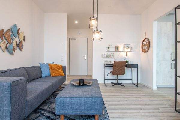 Beispiel eines offenen Wohnzimmer mit weißen Wänden, weißer Decke und holzfarbenen Vinylboden