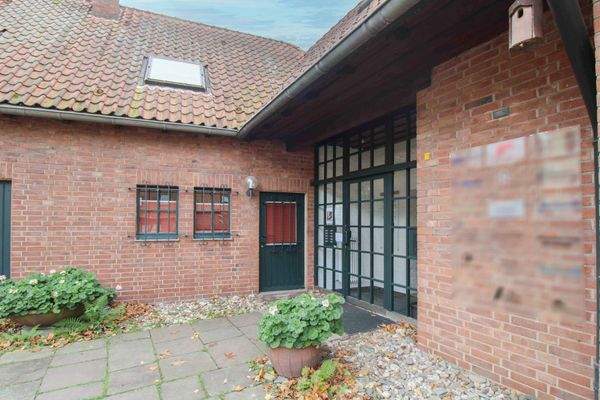 Stilvoller Eingangsbereich mit traditioneller Klinkerarchitektur und begrüntem Vorplatz