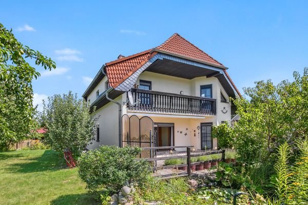 Blick auf das Haus mit Balkon, Terrasse und Gartenteich