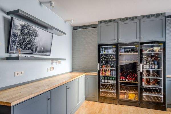 Edler Hauswirtschaftsraum mit integrieten Premium-Weinkühlschränken und Wand-TV