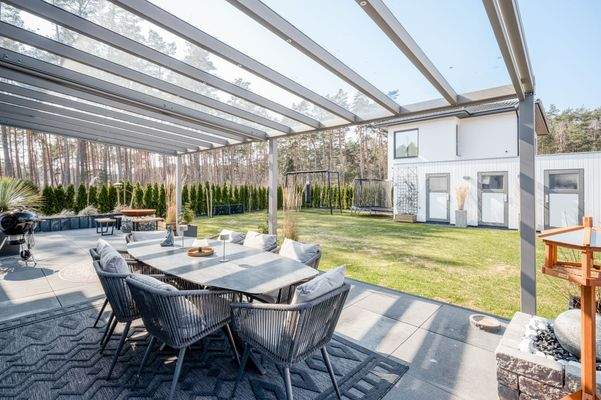 Großzügige, überdachte Terrasse mit Blick in den sonnigen Garten