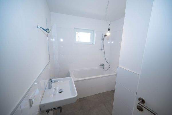 Bad mit Wanne, Waschmaschinenanschluss und Fenster