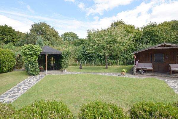 Ein Gartenhaus und eine Grillterrasse runden die Gartengestaltung ab