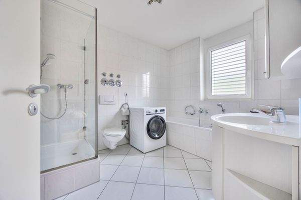 Bad en Suite | Hauptbadezimmer mit Wanne, Glasdusche und Waschmaschinenanschluss