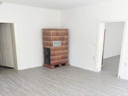 Wohnzimmer mit Kachelofen und Blick Richtung Schlafzimmer