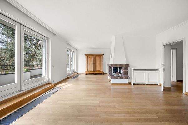 lichtdurchfluteter Wohnbereich mit zentralem Kamin und Zugang zum Balkon