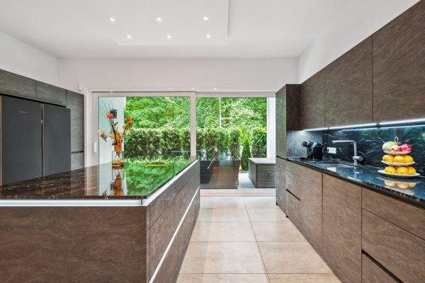 Blick in die High-End Küche mit Kochinsel, Miele Geräten und ausgeklügeltem Lichtkonzept