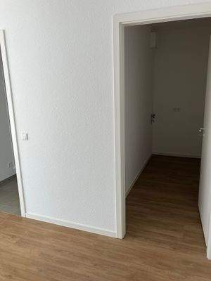 Blick in den Hauswirtschaftsraum mit Waschmaschinenanschluss, weiß angelegten Wänden und braunem Vinyl-Designboden in Holzoptik