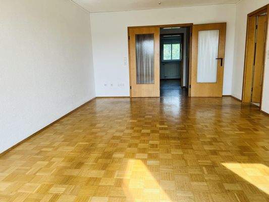 Wohnzimmer mit Parkett und zwei Türen zum Flur