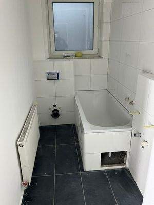 Badezimmer mit weißen Fliesen und Badewanne, Heizkörper