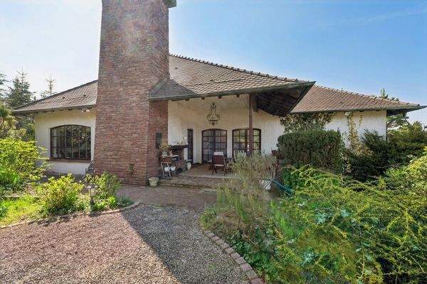 Exklusive Gartenansicht mit überdachter Terrasse und Kamin